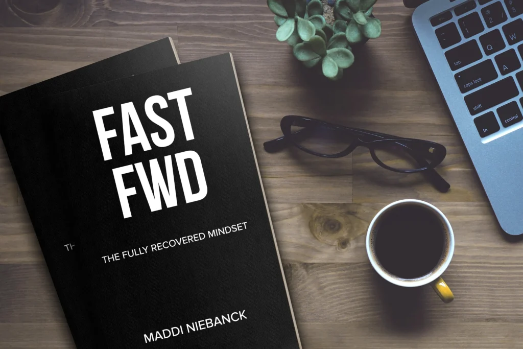 Fast Fwd The fully Recovered Mindset Book on a table with a laptop and a cup of coffee in front of a pair of glasses